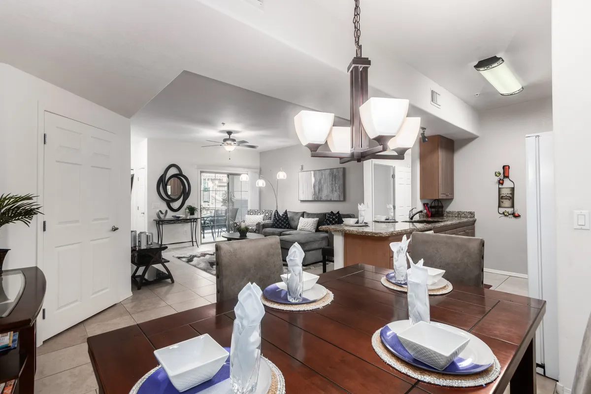 A warmly lit dining area with an elegantly set dining table, decorative wall art, and an open layout connecting to the living space. The setting is ready for family meals or gatherings, capturing the essence of togetherness and celebration.