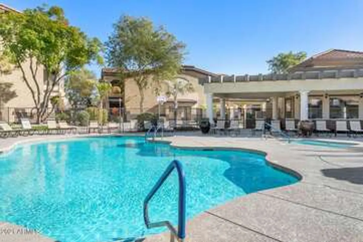 A sparkling heated community pool bordered by inviting lounge chairs and mature trees. The pool area is surrounded by the building's distinctive architecture, creating a relaxing yet lively atmosphere that encourages families to swim, sunbathe, or socialize after a day of exploring.
